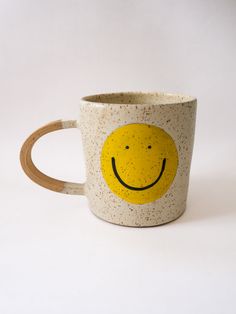 a coffee cup with a smiley face painted on the outside and inside, sitting on a white surface