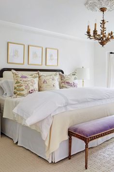 a bedroom with a bed, chandelier and two pictures on the wall above it