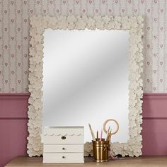 a mirror sitting on top of a wooden table next to a drawer and brush holder