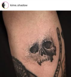 a black and white photo of a skull on someone's leg with ink splatters all over it