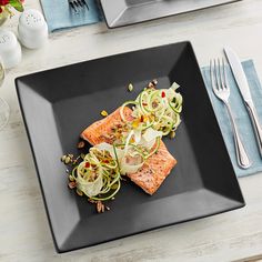 a black plate topped with salmon and veggies