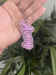 a person is holding a pink keychain with the word boooo on it