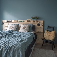 a bed with blue sheets and pillows in a bedroom next to a wooden headboard