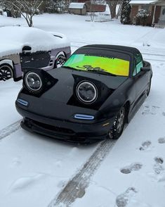 a black car parked on the side of a road covered in snow