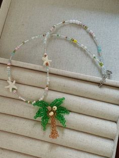 a beaded palm tree and starfish necklace is displayed on a window sill