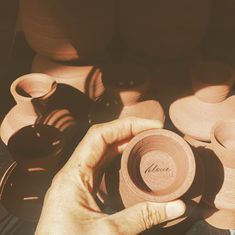 a person holding a brown hat in front of many pottery pots and bowls on a table