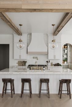 a large kitchen with white cabinets and wooden stools in front of the counter top