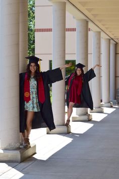 two women in graduation gowns and caps are posing for the camera on some pillars