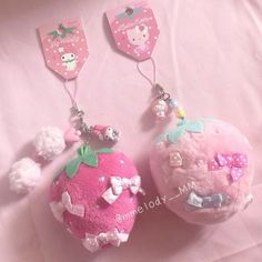 two stuffed animals are hanging from key chains on a pink background with white pom poms