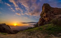 the sun is setting on top of a mountain with mountains in the backgroud