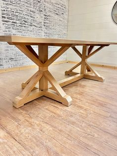 a wooden table sitting on top of a hard wood floor next to a brick wall