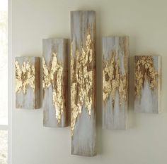 three gold leaf paintings on a white wall next to a window in a living room