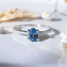 a blue ring sitting on top of a table next to some white flowers and shells