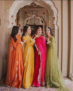 three women in colorful dresses standing next to each other with their arms around one another