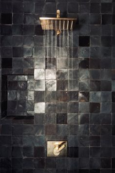 a shower head with water flowing from it's spout in a tiled wall