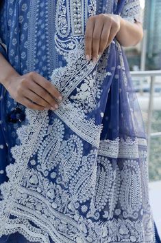 a woman is wearing a blue and white dress with intricate lace on the bottom half