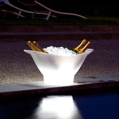 a bowl filled with ice and two bottles of champagne sitting on top of a pool