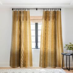 a living room with a white rug and yellow curtains hanging on the windowsills