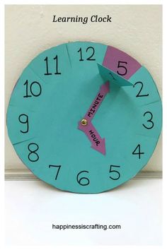 a blue clock with pink tape on the face and words learning clock written across it