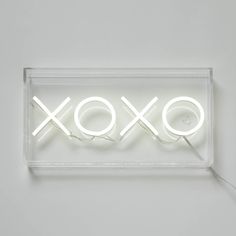 a neon sign with the word xoxo on it's side in front of a white wall