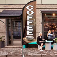 two women sitting at a table in front of a coffee shop on the side walk