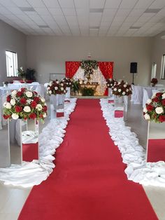 a red carpeted aisle with white and red flowers on each side, surrounded by chairs