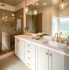 a large bathroom with two sinks and gold faucets on the countertop, along with a walk in shower