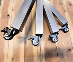 three metal casteors on a wooden floor with one holding the other's wheels