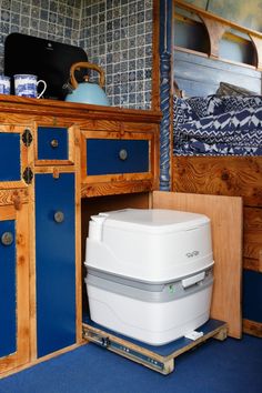 a white and blue cooler sitting on top of a wooden cabinet next to a bed