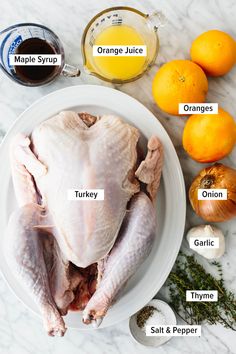 a white plate topped with chicken next to oranges and other ingredients