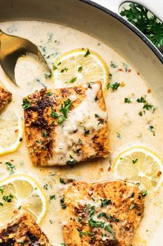 three pieces of fish covered in sauce and garnished with parsley next to lemon wedges