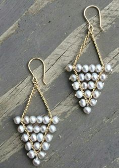 two pairs of earrings with pearls hanging from them on a piece of wooden planks