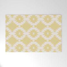 a yellow and white rug with an abstract pattern on the bottom, in front of a white wall