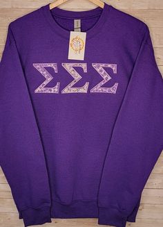 a purple sweatshirt with the greek letter k is shown on a wooden hanger,