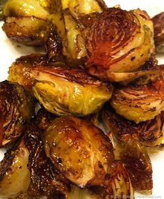 roasted brussel sprouts on a white plate with brown sauce drizzled over them