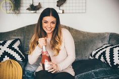 a woman sitting on a couch holding a bottle of ketchup in her hand