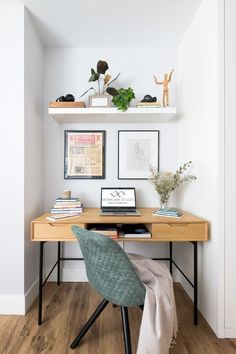 a desk with a laptop on top of it and some pictures above the desk in front of it