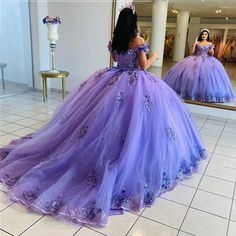 a woman in a purple ball gown looking at herself in the mirror