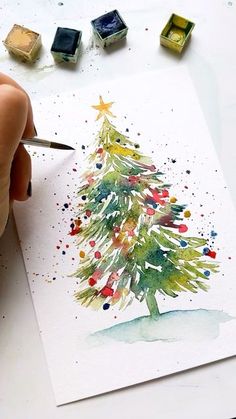 someone is painting a christmas tree with watercolors