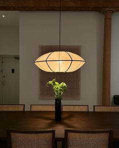 a dining room table with chairs and a vase filled with flowers sitting on top of it