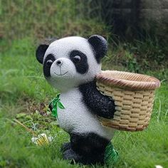 a panda bear figurine holding a basket in its mouth and sitting on the grass