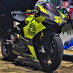 a yellow and black motorcycle parked in front of a gas station sign with the number 33 on it