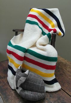 a knitted blanket sitting on top of a wooden table next to a stuffed animal