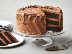 a chocolate cake with one slice missing from it and another piece on the plate next to it