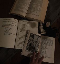 an open book sitting on top of a wooden table next to a candle and some books