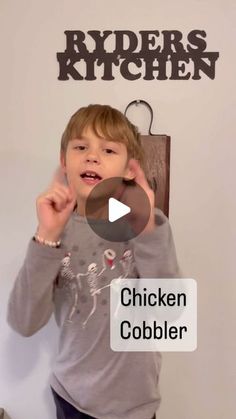 a young boy standing in front of a kitchen sign