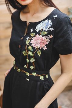 ❤ The black linen hand embroidered dress is very soft, skin friendly, breezy and comfortable.  ❤ Item description: - A lovely, unique and elegant dress with colourful embroidered climber tree and hydrangea motifs. - Material: linen, coconut button, embroidery threads. - Environmentally friendly. - This dress is very useful, go with any outfit, that can be used to go to school, go out, go shopping.    It is a perfect gift for yourself or your beloved.  ❤ Care instructions:     The best way to wash embroidery cloth is to put it in soapy water (with a mild detergent and cold water at 86 ºF/30oС) for 20 minutes. Try to not wash the item with other clothing that might cause damage, such as zippers, buttons or different colors. You wash it by hand, and if you have dirty patches on your garment, Gentle Outfits Women, Black Clothes Outfits For Women, Black Cloth Embroidery, Embroidered Wrap Dress, Embroidery On Linen Dress, Embroidery On Dress Ideas, Black Dress With Embroidery, Dress Embroidery Ideas, Linen Dress Embroidery Ideas