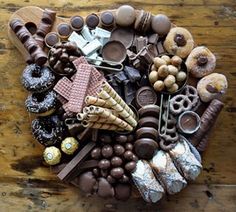 a wooden table topped with lots of different types of chocolates and pastries on top of each other