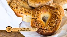 several bagels sitting on top of white wax paper in a basket next to each other