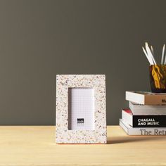 two books are stacked on top of each other next to a small white photo frame